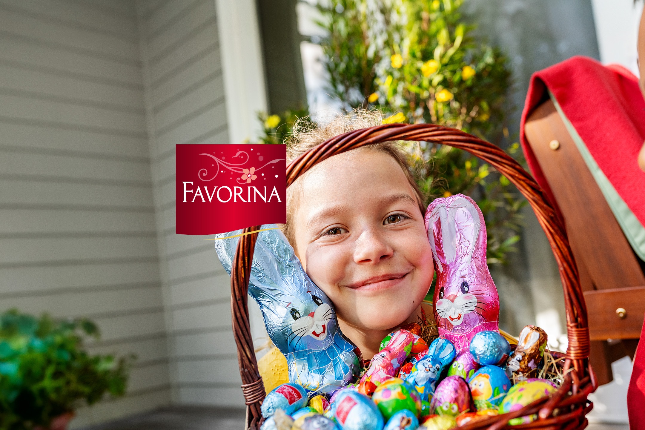 Lächelndes Kind mit Osterkorb voller Schokohasen und Eiern.
