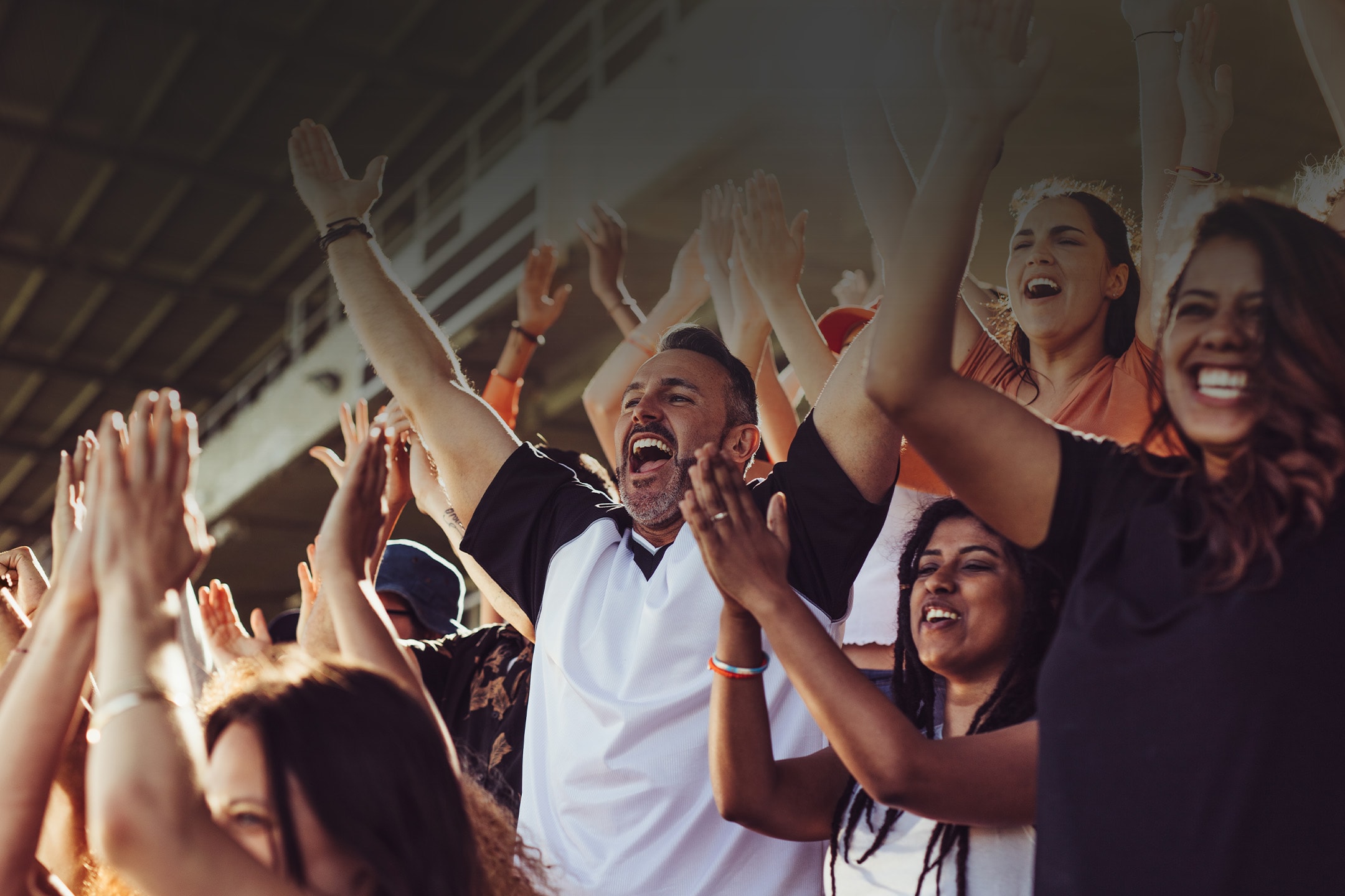 Tifosi sportivi entusiasti applaudono e urlano di gioia in uno stadio.