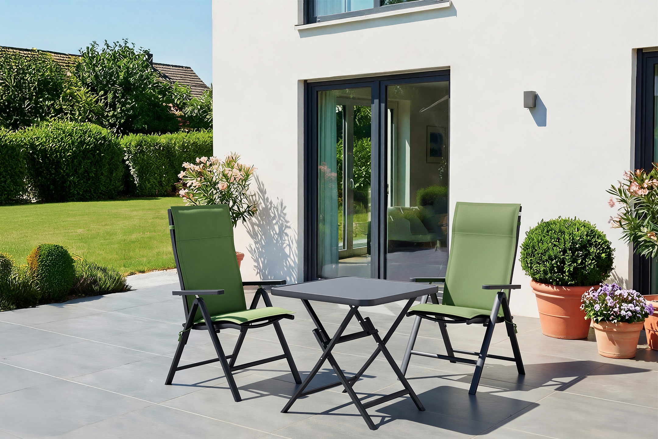 Klappbares Balkonset mit Tisch und zwei grünen Stühlen auf einer Terrasse.