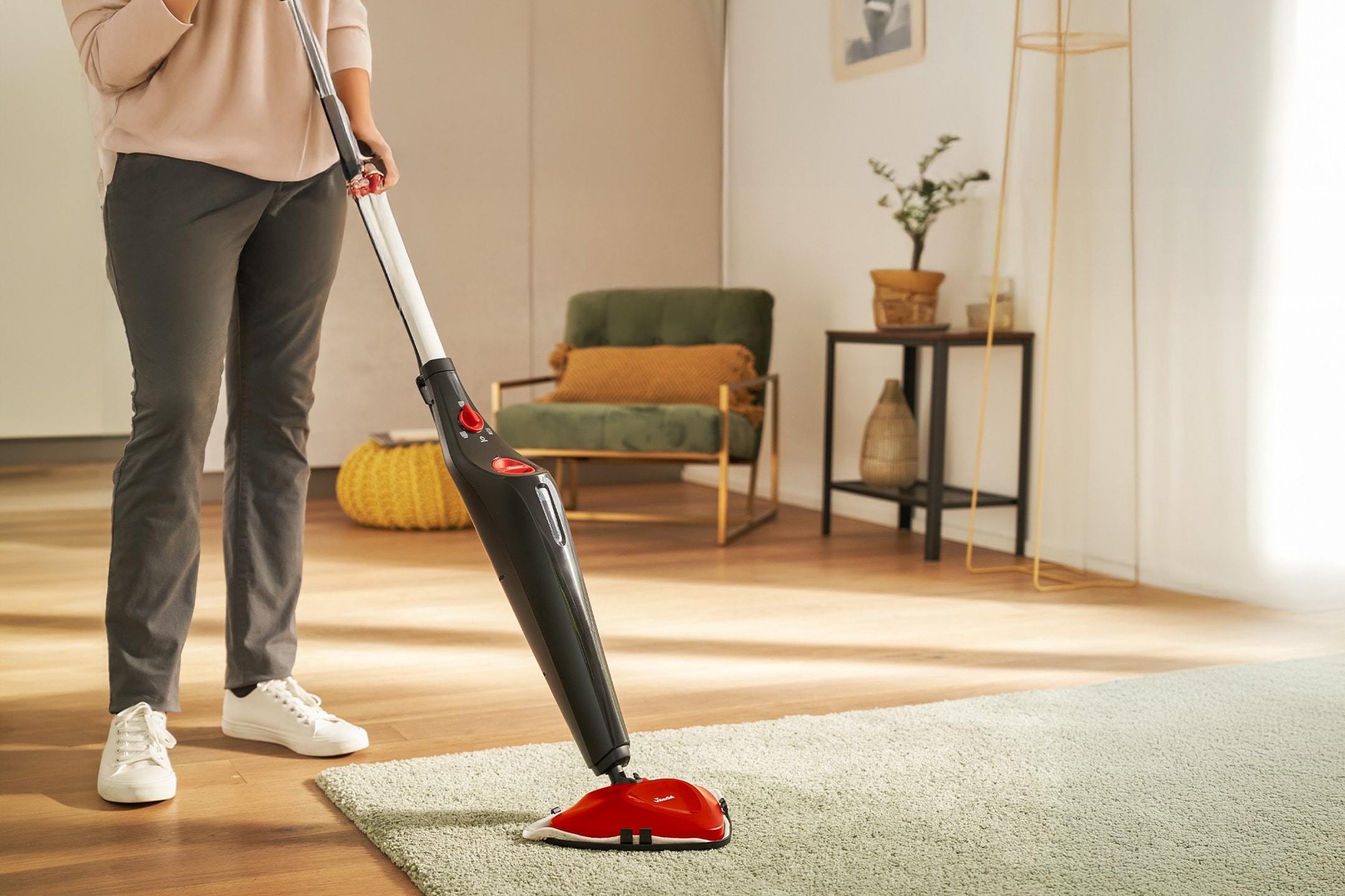 Femme nettoyant un tapis avec un nettoyeur vapeur dans un salon lumineux.