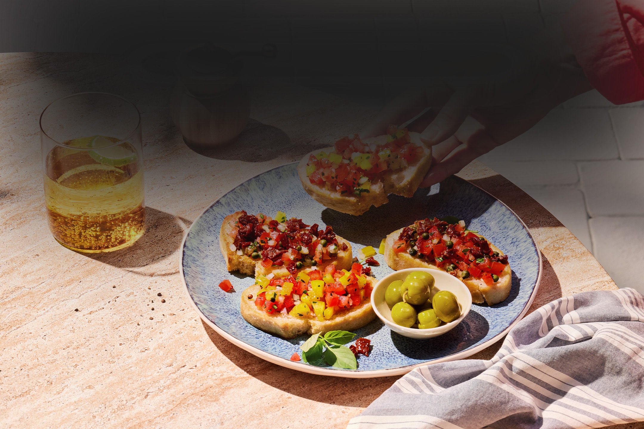 Bruschetta mit Tomaten und Oliven, dazu ein Glas Limonade auf einem Tisch.