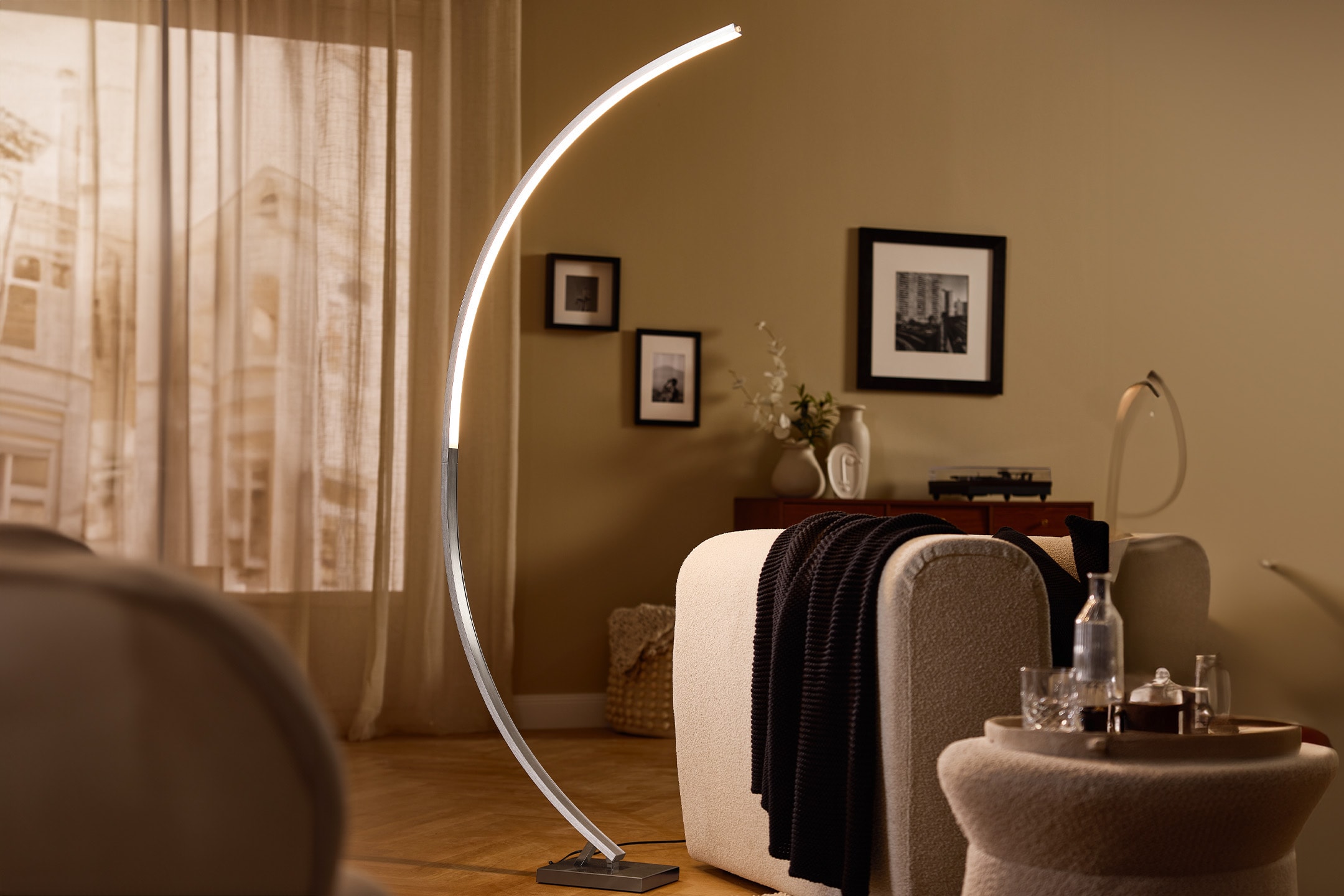 Modernes Wohnzimmer mit Stehlampe, Sessel, Beistelltisch und Bildern an der Wand.