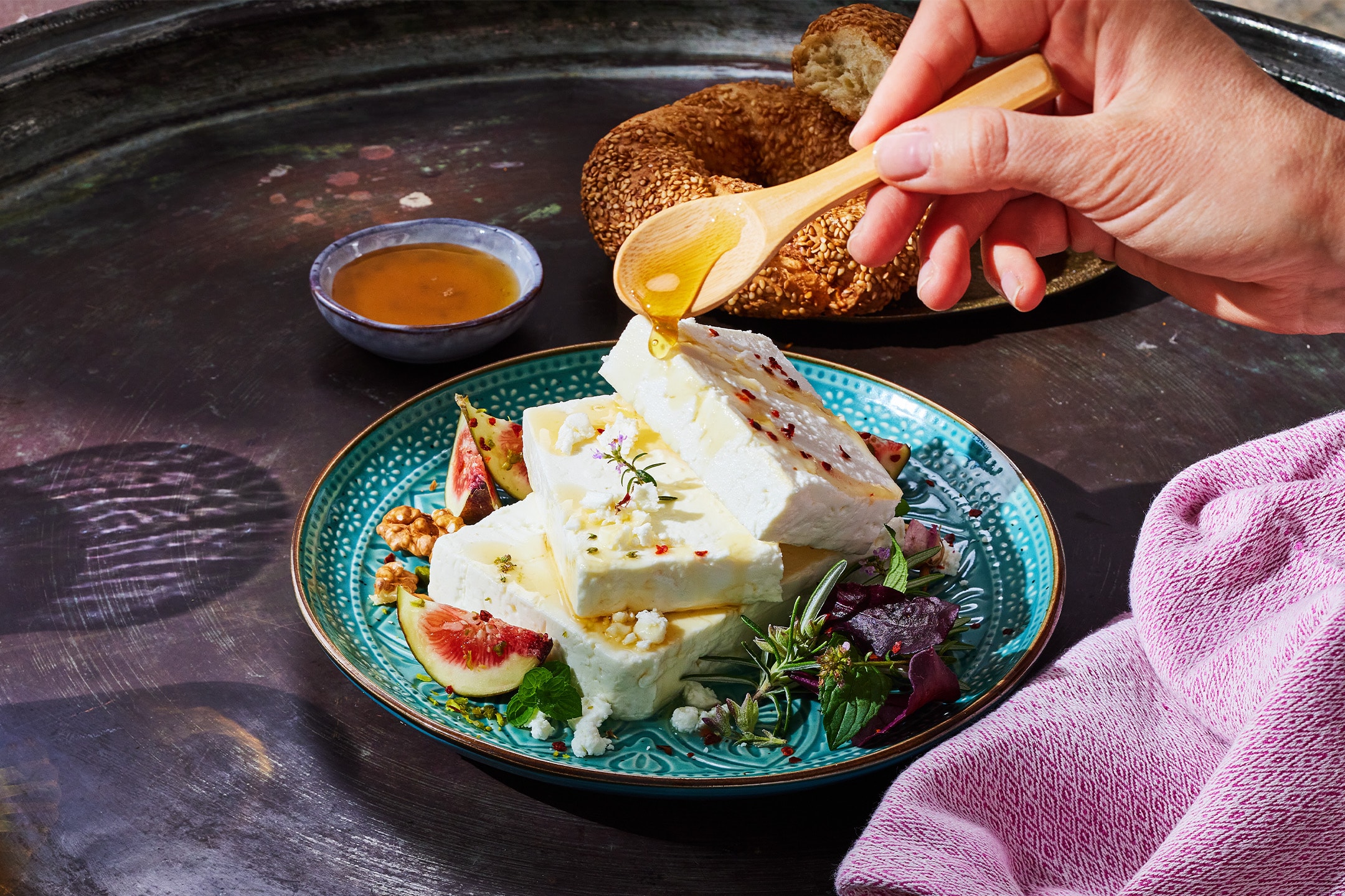 Honig über Feta-Käse mit Feigen, Walnüssen und Simit auf einem dunklen Tablett gegossen.