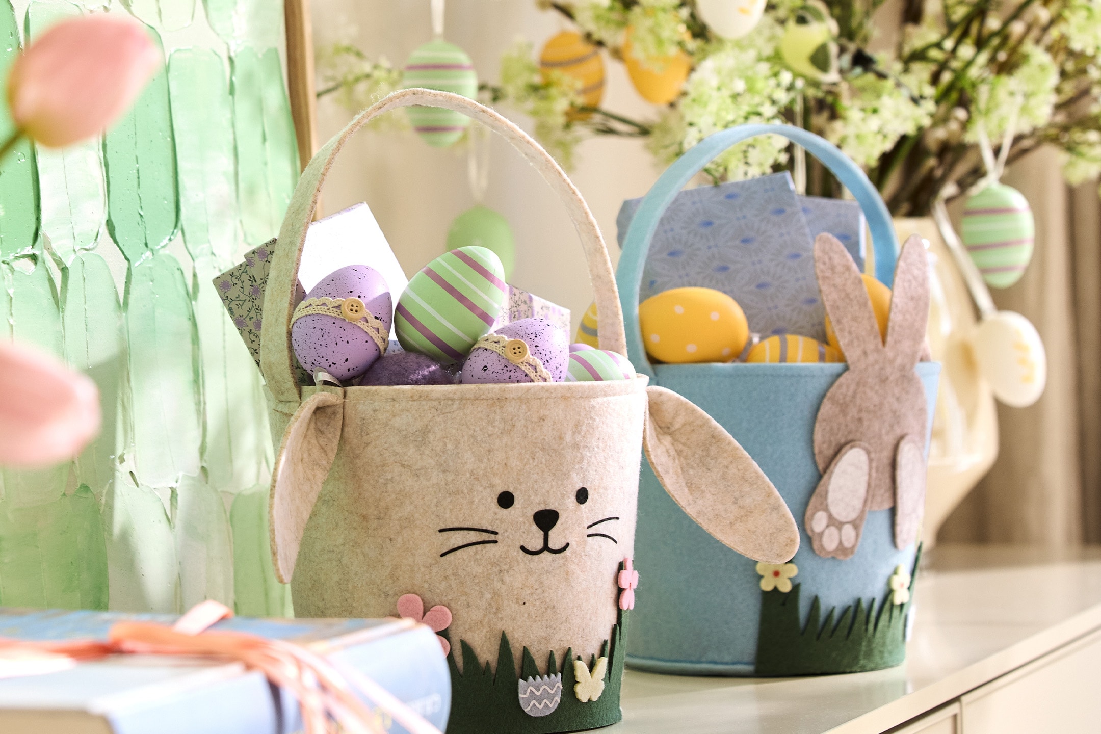 Osterkörbe in Hasenform gefüllt mit bunten Eiern, auf einer Kommode stehend.