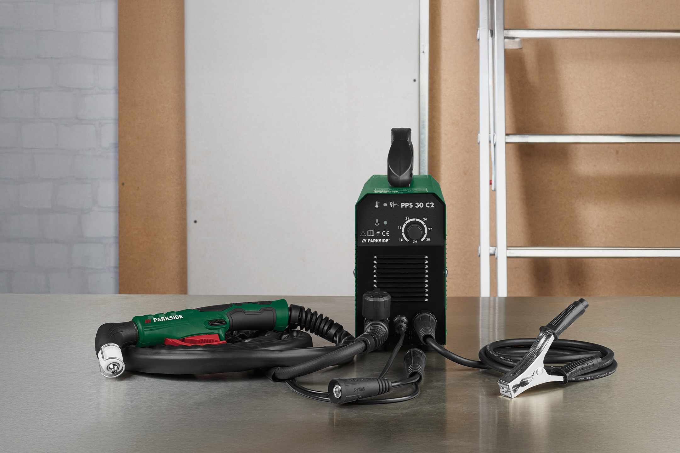 Plasmaschweißgerät mit Brenner und Masseklemme auf einem Metalltisch.