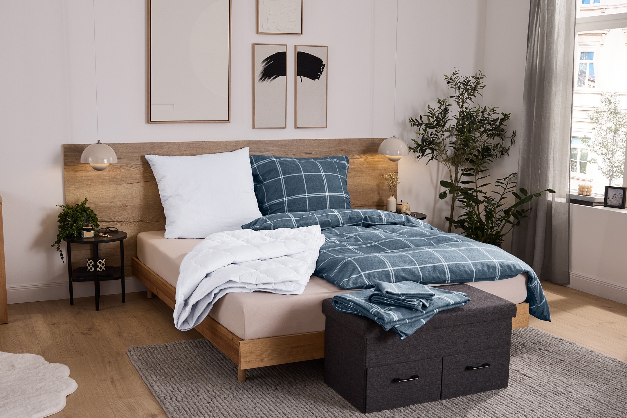 Modernes Schlafzimmer mit Holzbett, blauer karierter Bettwäsche und grauer Aufbewahrungsbox.