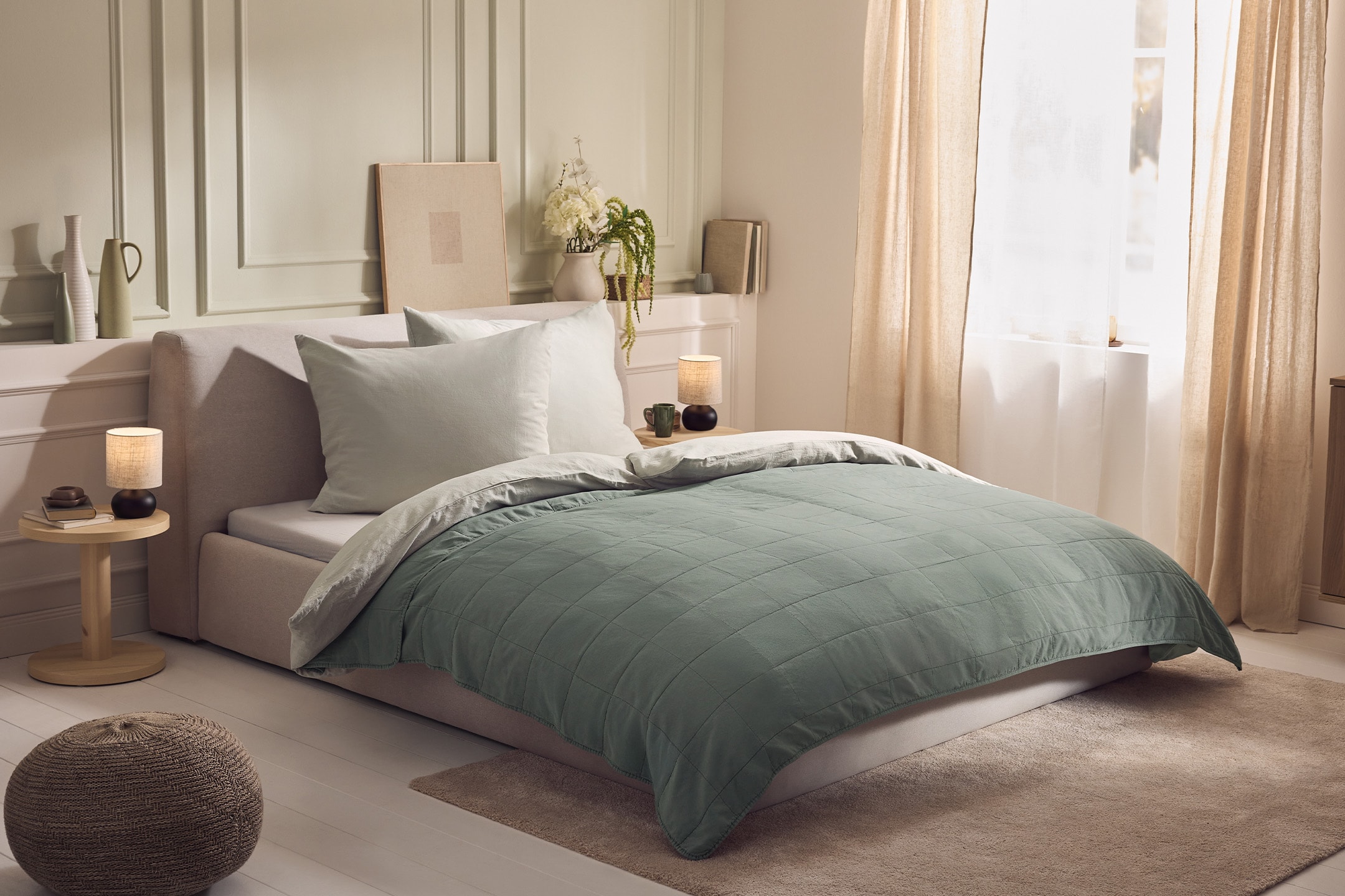 Camera da letto con letto matrimoniale, copriletto verde, cuscini bianchi e comodini con lampade.