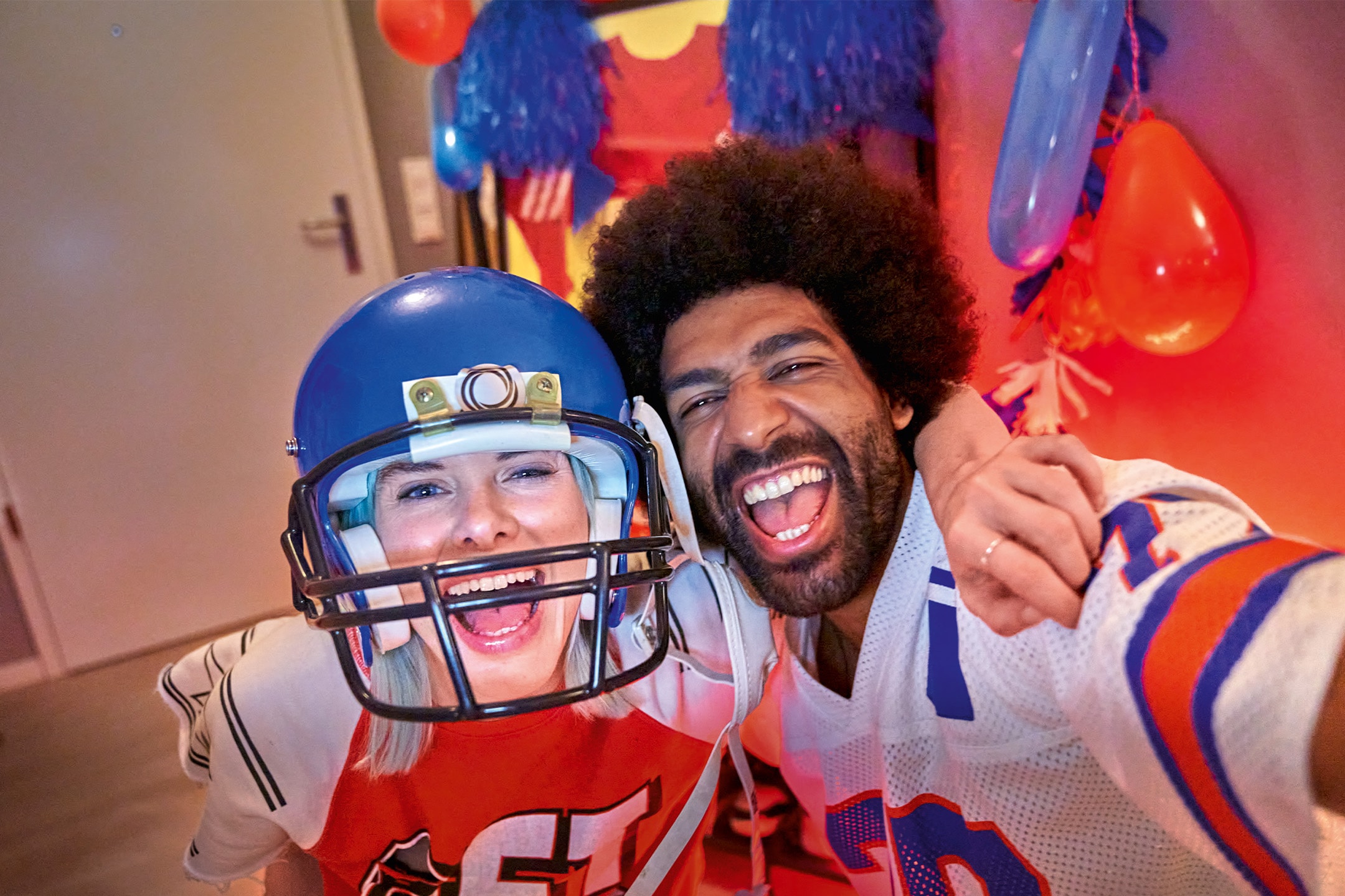 Deux amis souriants, l'un portant un casque de football américain, l'autre un maillot de sport.