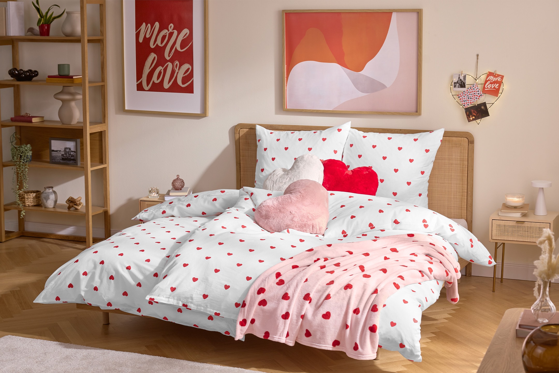 Schlafzimmer mit Bettwäsche und Decke mit Herzmotiv, dazu passende Deko und Bilder.