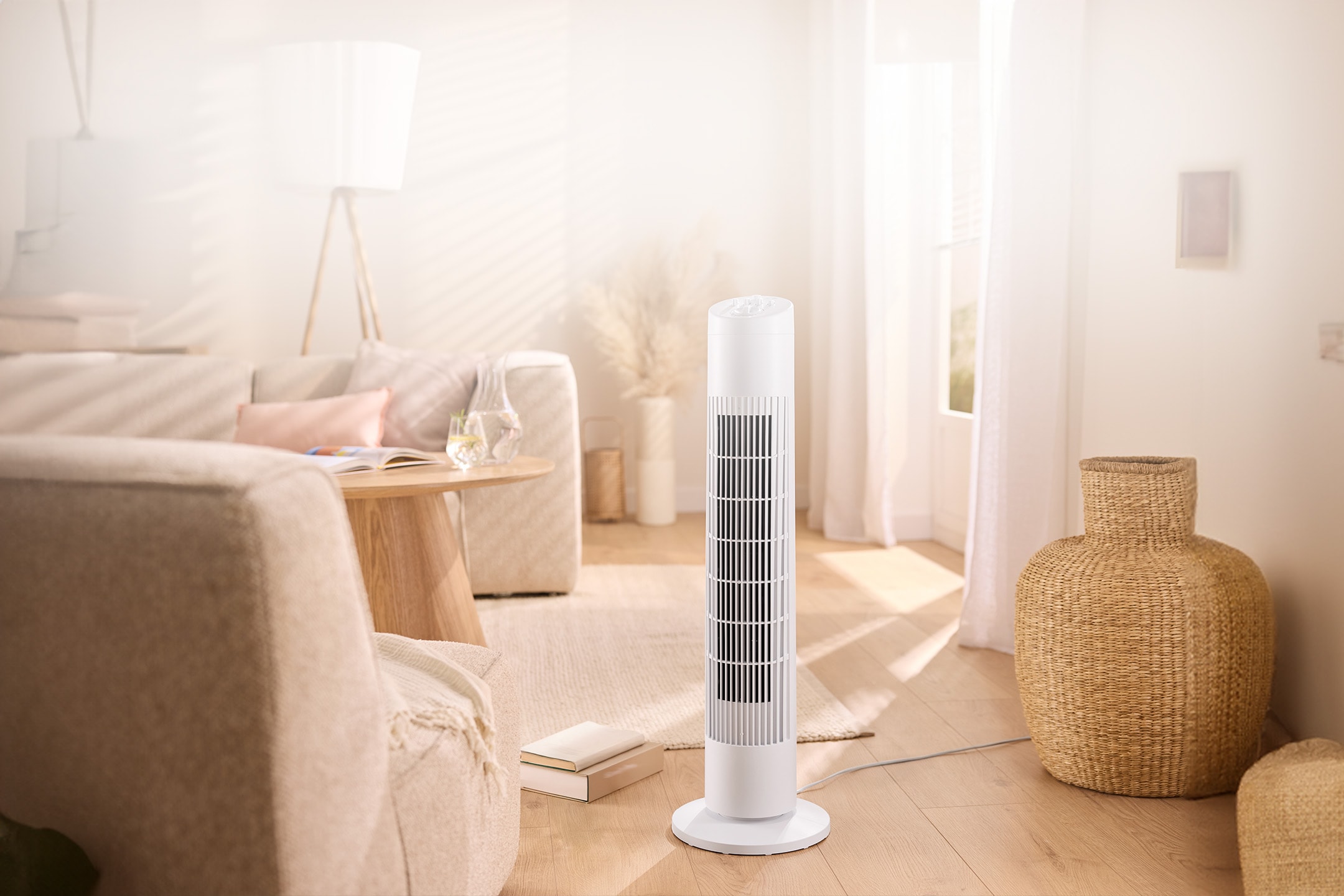 Weißer Turmventilator in einem hellen Wohnzimmer mit Sofa und Couchtisch.