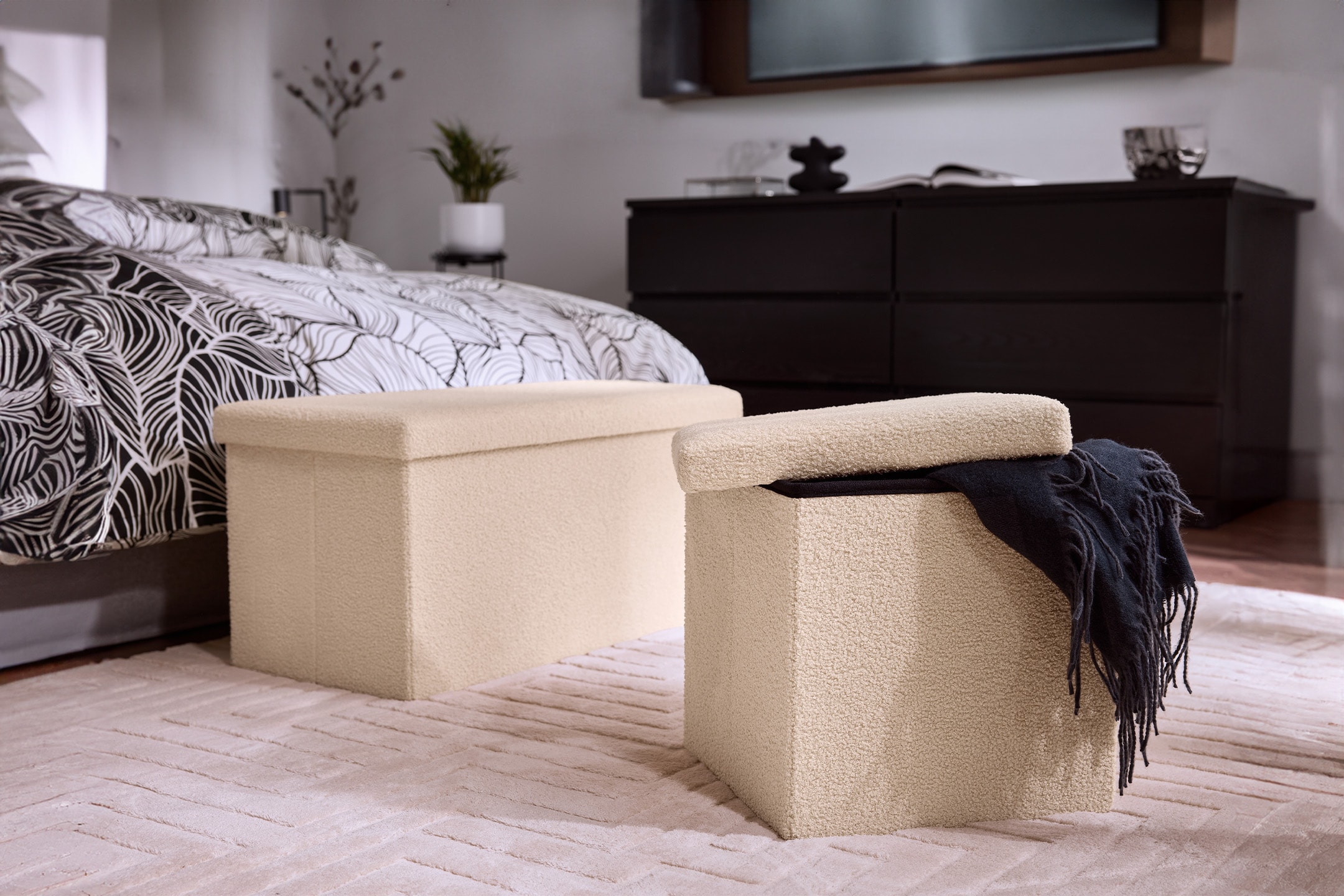 Zwei cremefarbene Aufbewahrungshocker auf einem Teppich in einem Schlafzimmer.