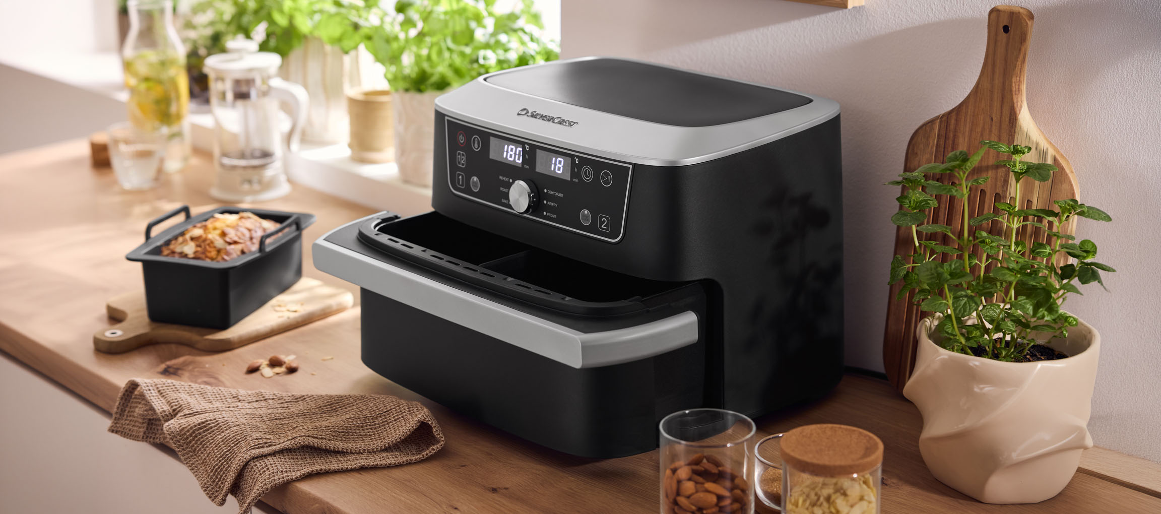 Friteuse à air noire avec four double et pâtisserie sur un comptoir en bois.