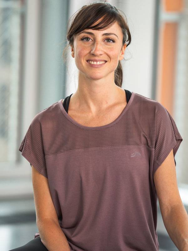 Donna sorridente che indossa un top sportivo viola a maniche corte.