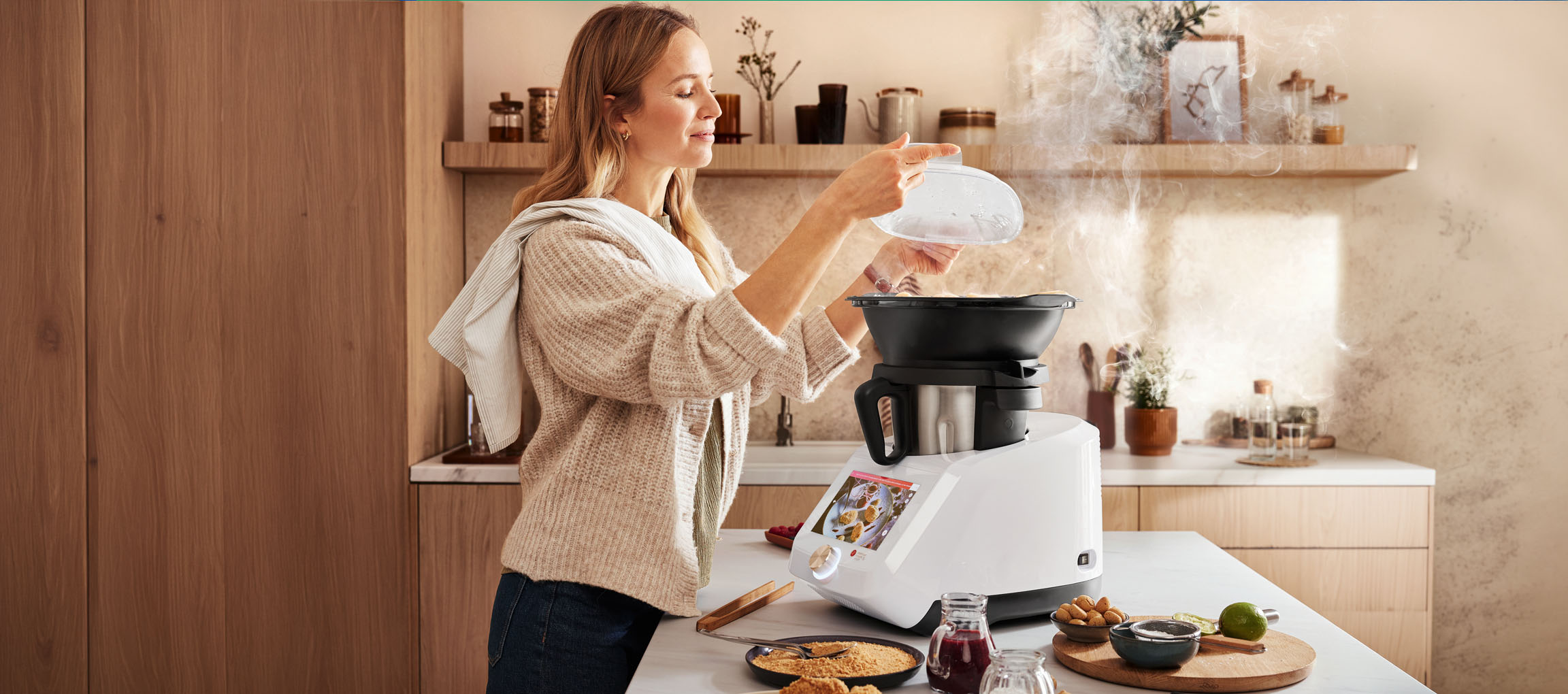 Femme cuisinant avec un robot de cuisine, vapeur s'élevant, dans une cuisine moderne.