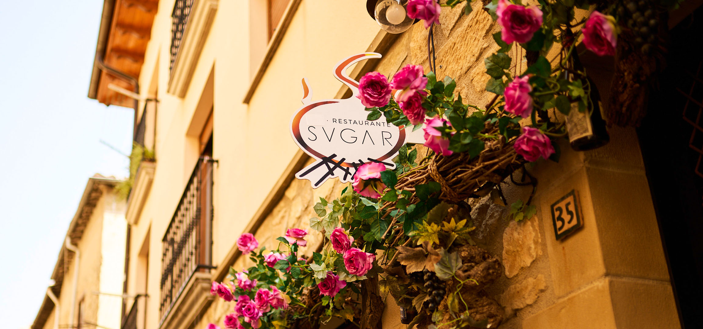 Enseigne du restaurant «SVGAR» avec des fleurs roses sur un mur en pierre