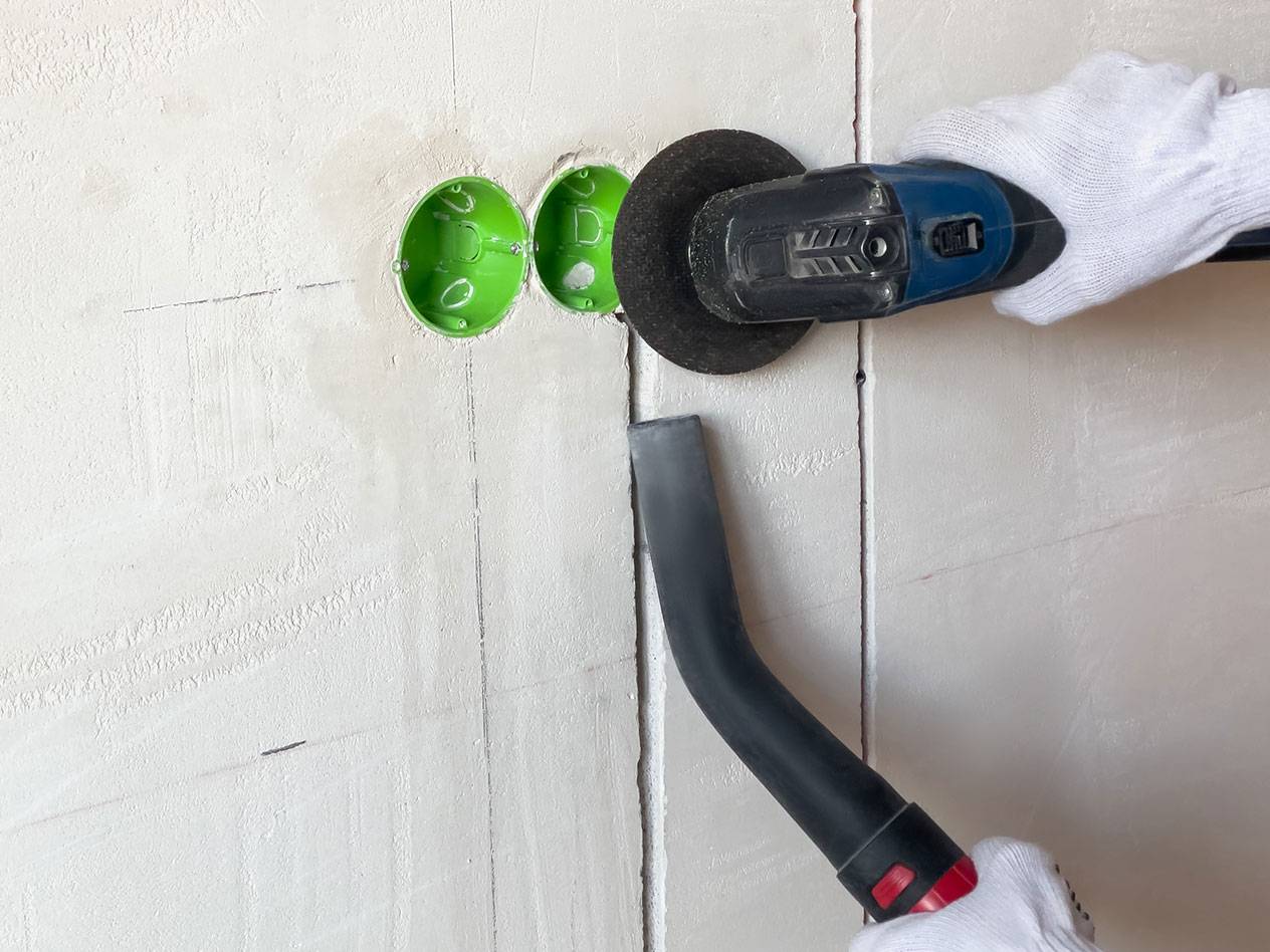 Utensile elettrico taglia scanalature in un muro con un aspirapolvere per la polvere.