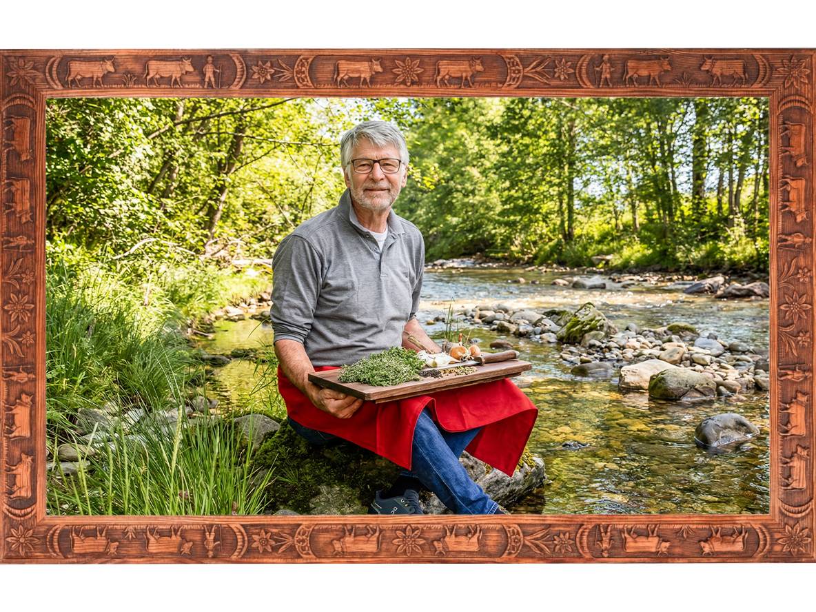 Uomo con erbe fresche e verdure in riva al fiume, incorniciato da una cornice di legno intagliato.