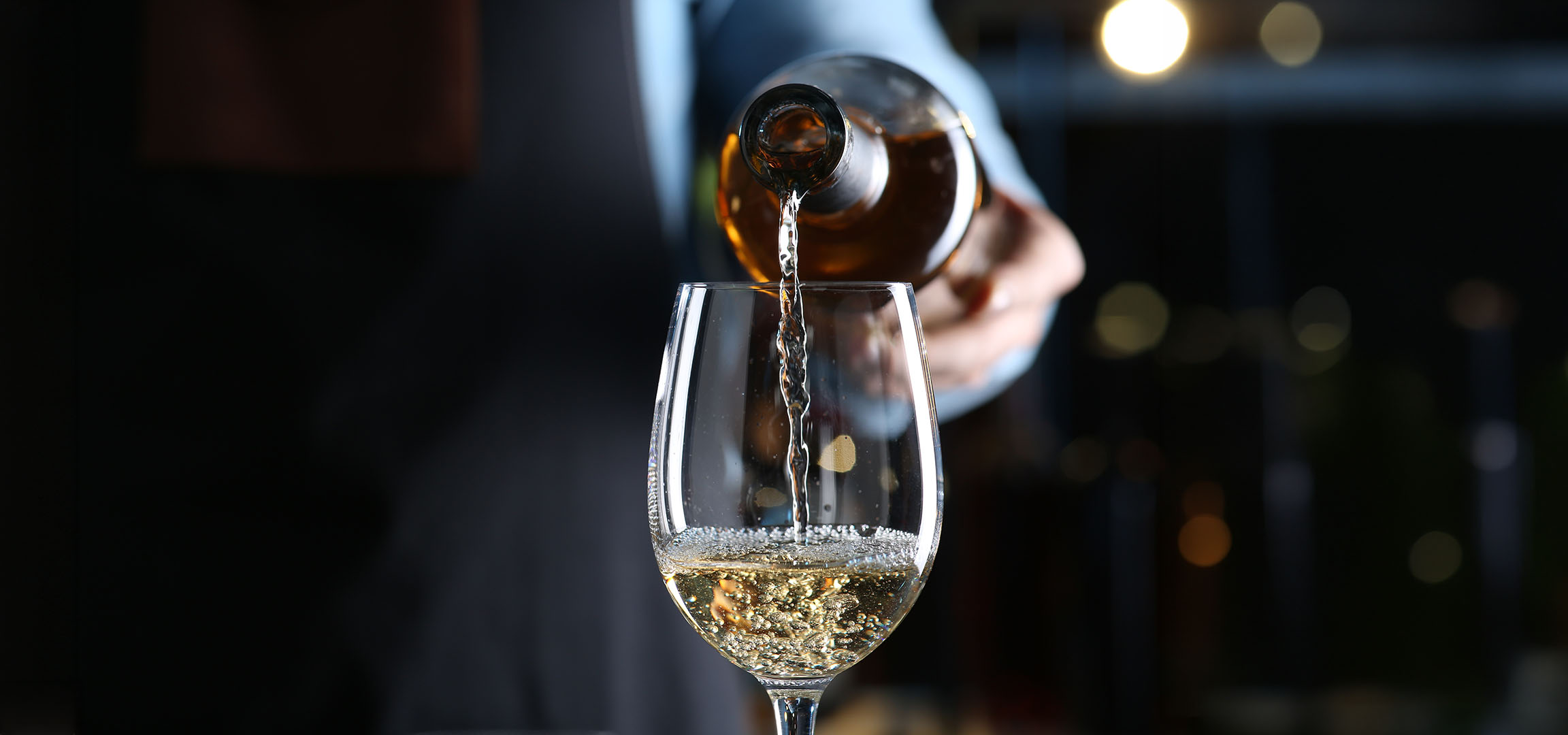 Weißwein wird in ein Glas gegossen.