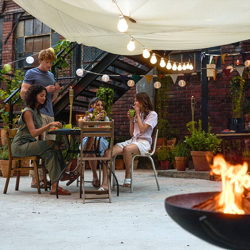Des amis profitent d'un dîner en plein air sous les lumières.