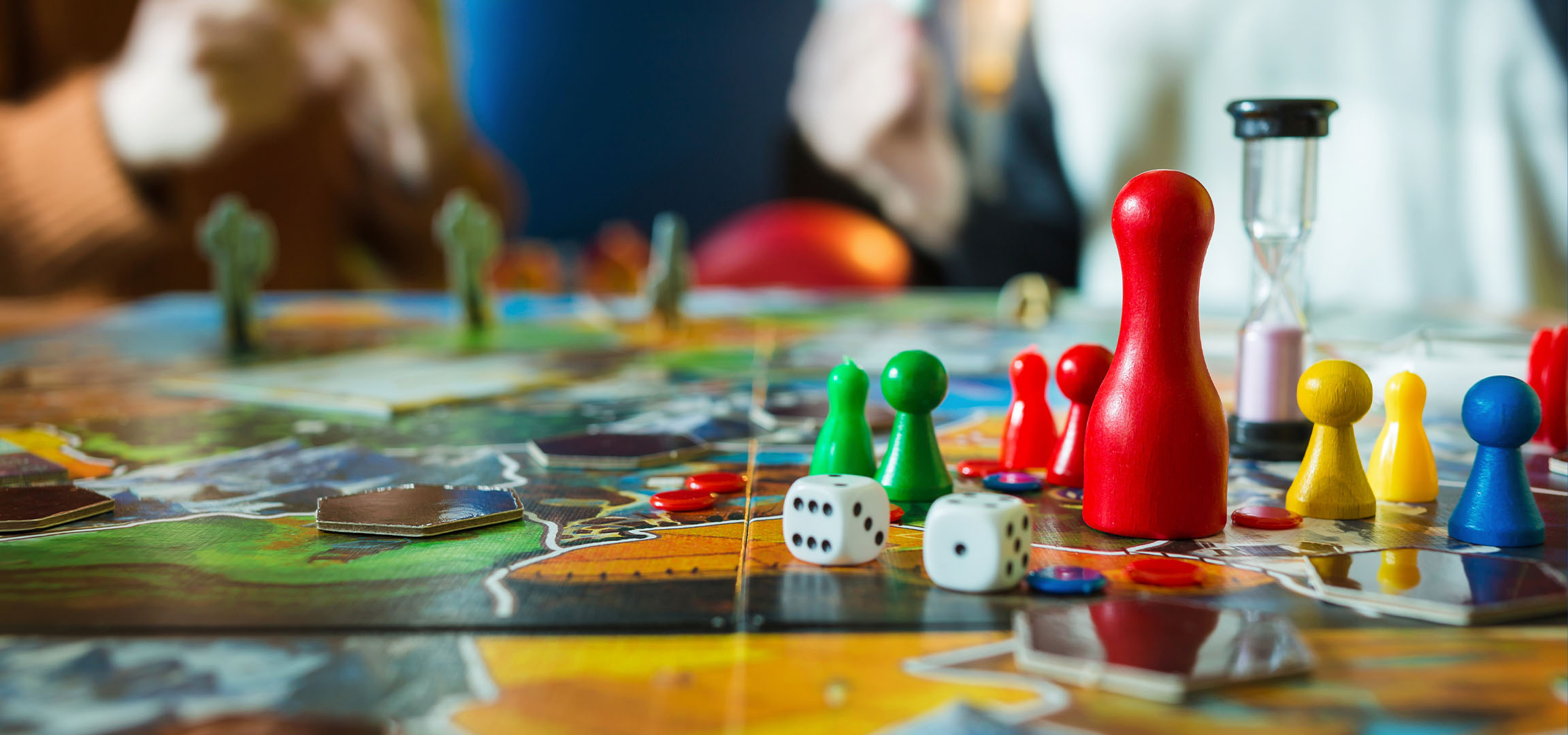 Pezzi colorati di gioco da tavolo, inclusi pedoni rossi, verdi, gialli e blu, con dadi.