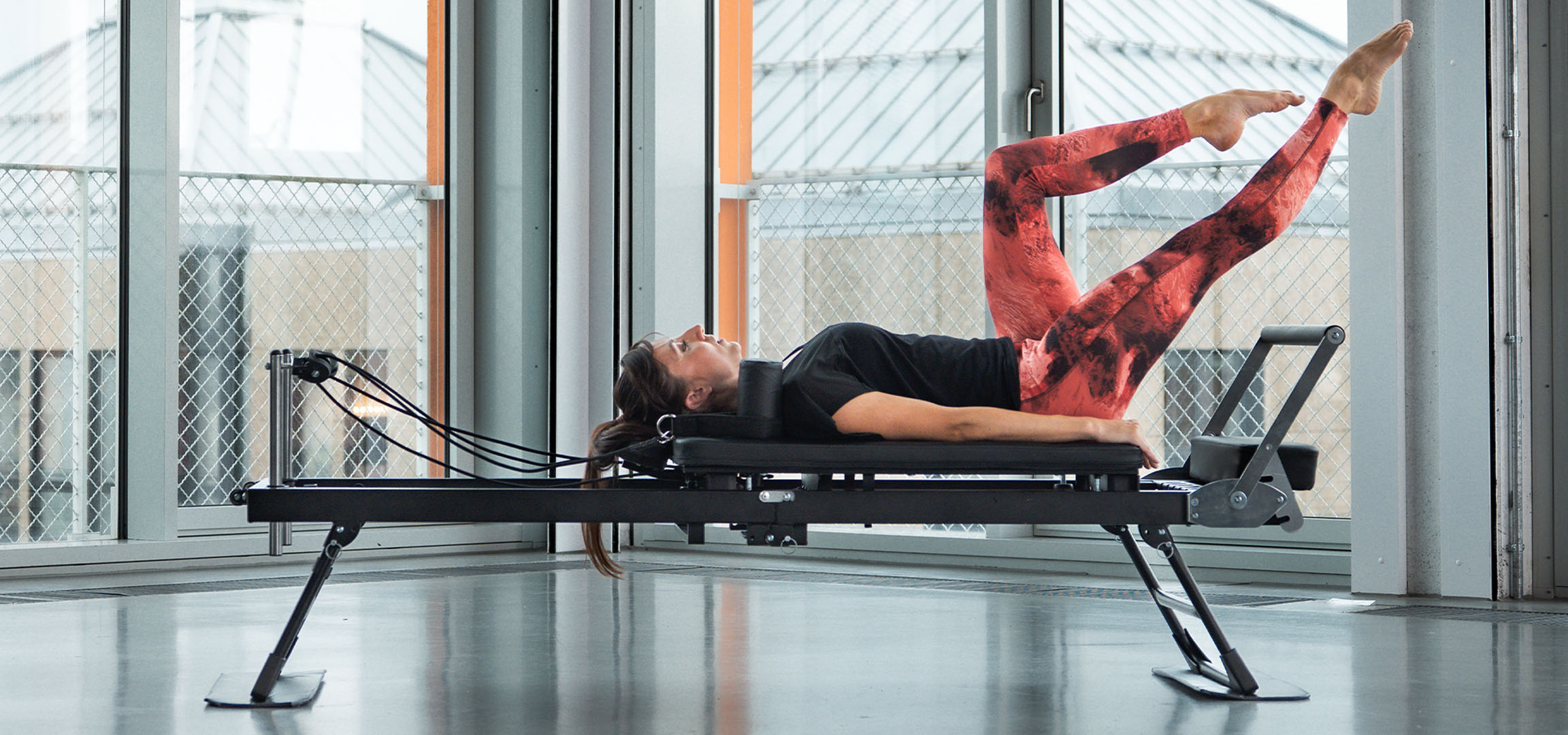 Donna che fa Pilates su una macchina reformer, con accessori fitness nelle vicinanze.