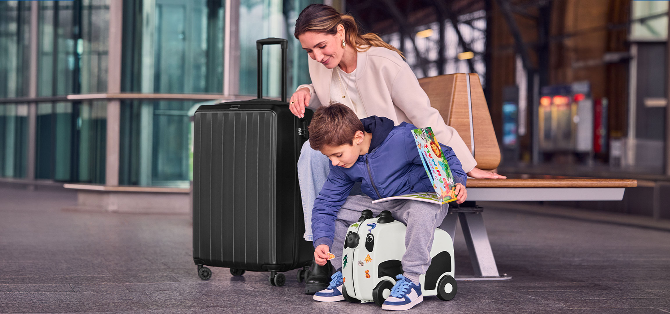 Mère et enfant avec des bagages à l'aéroport, l'enfant jouant avec une valise à roulettes.