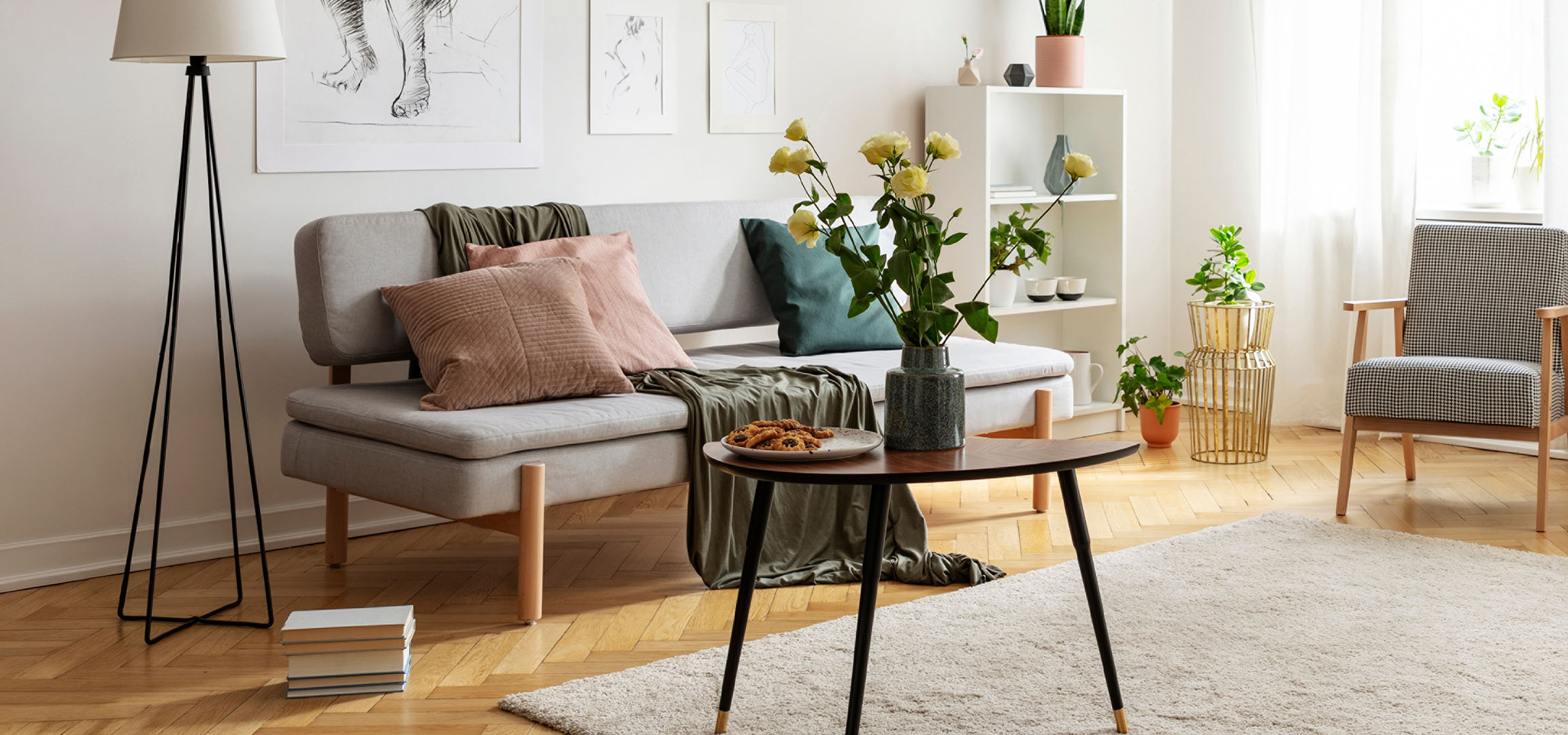 Gemütliches Wohnzimmer mit grauem Sofa, Kissen, Couchtisch mit Keksen und Blumenvase.