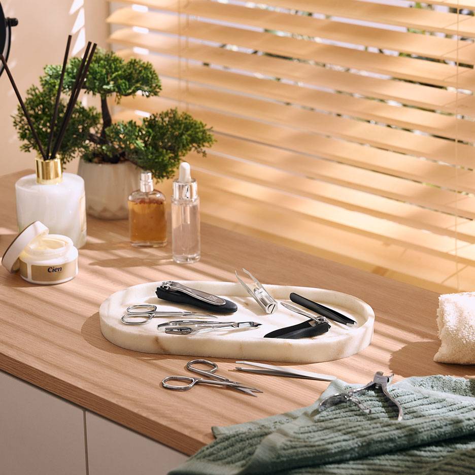 Maniküre-Set auf Marmortablett, mit Kosmetik und Pflanzen auf Holzoberfläche.