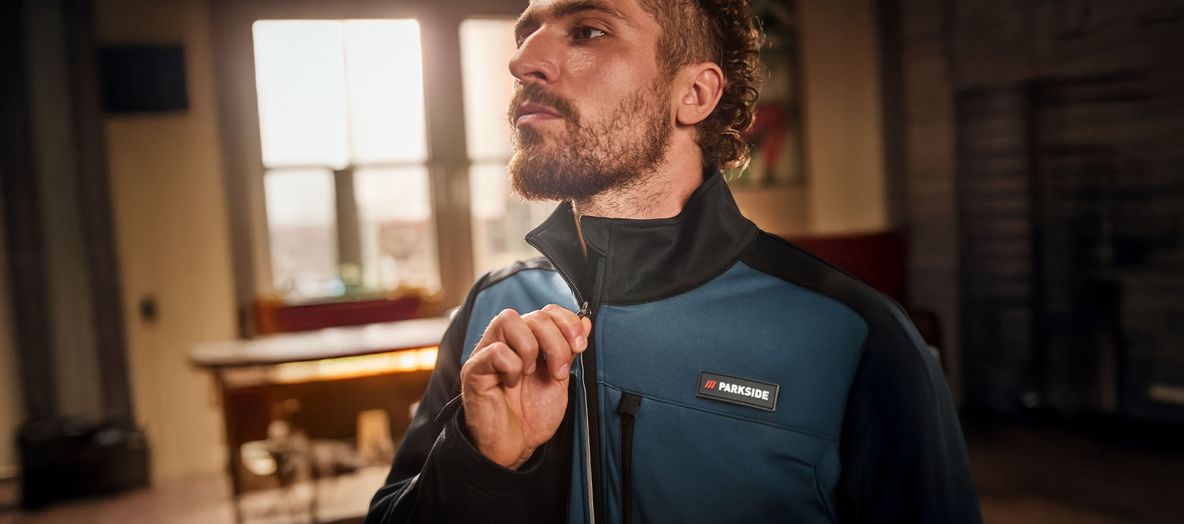 Homme en veste de travail Parkside bleue et noire en train de la fermer