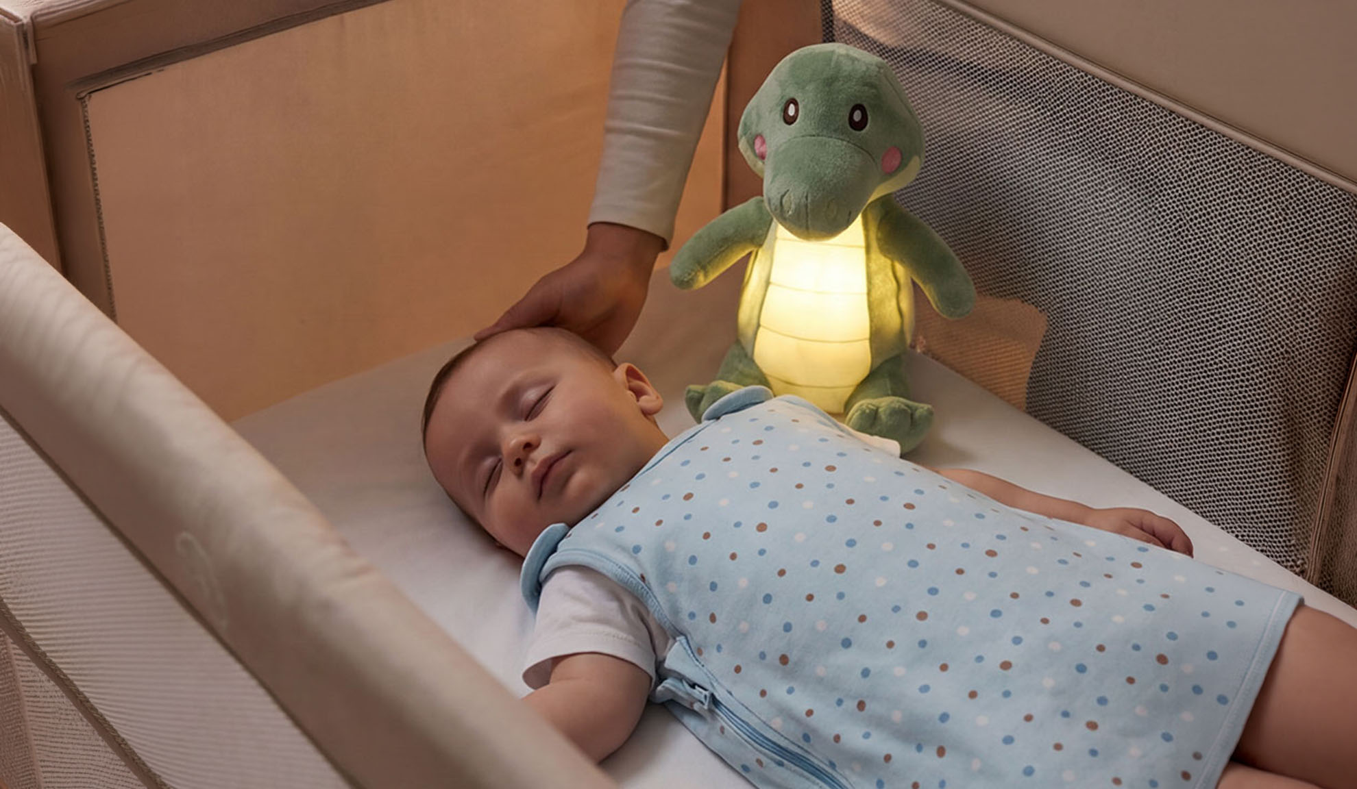 Bébé dormant dans un lit avec une peluche et la main d'un parent.