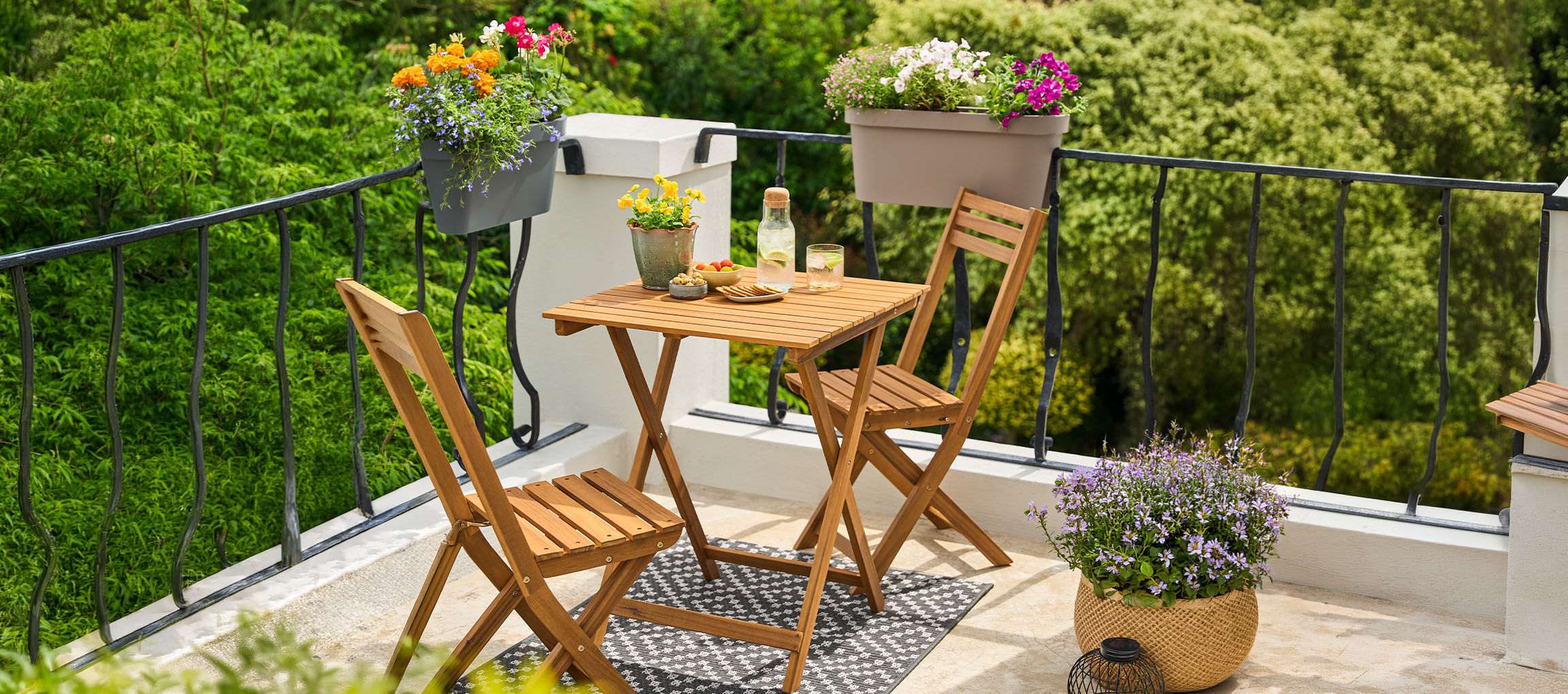 Balkonmöbel-Set mit Klapptisch und Stühlen, dekoriert mit Blumentöpfen.
