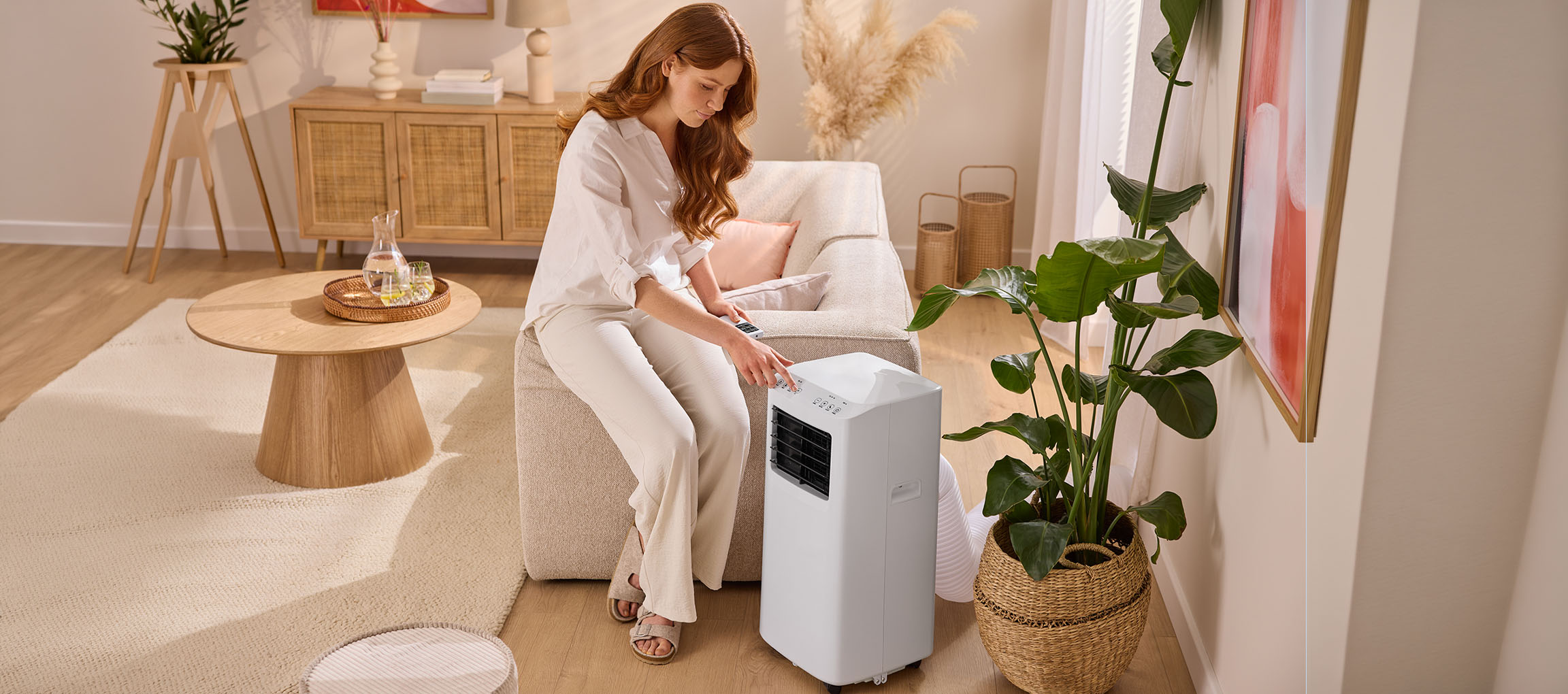 Frau stellt eine mobile Klimaanlage in einem Wohnzimmer mit Sofa und Couchtisch ein.