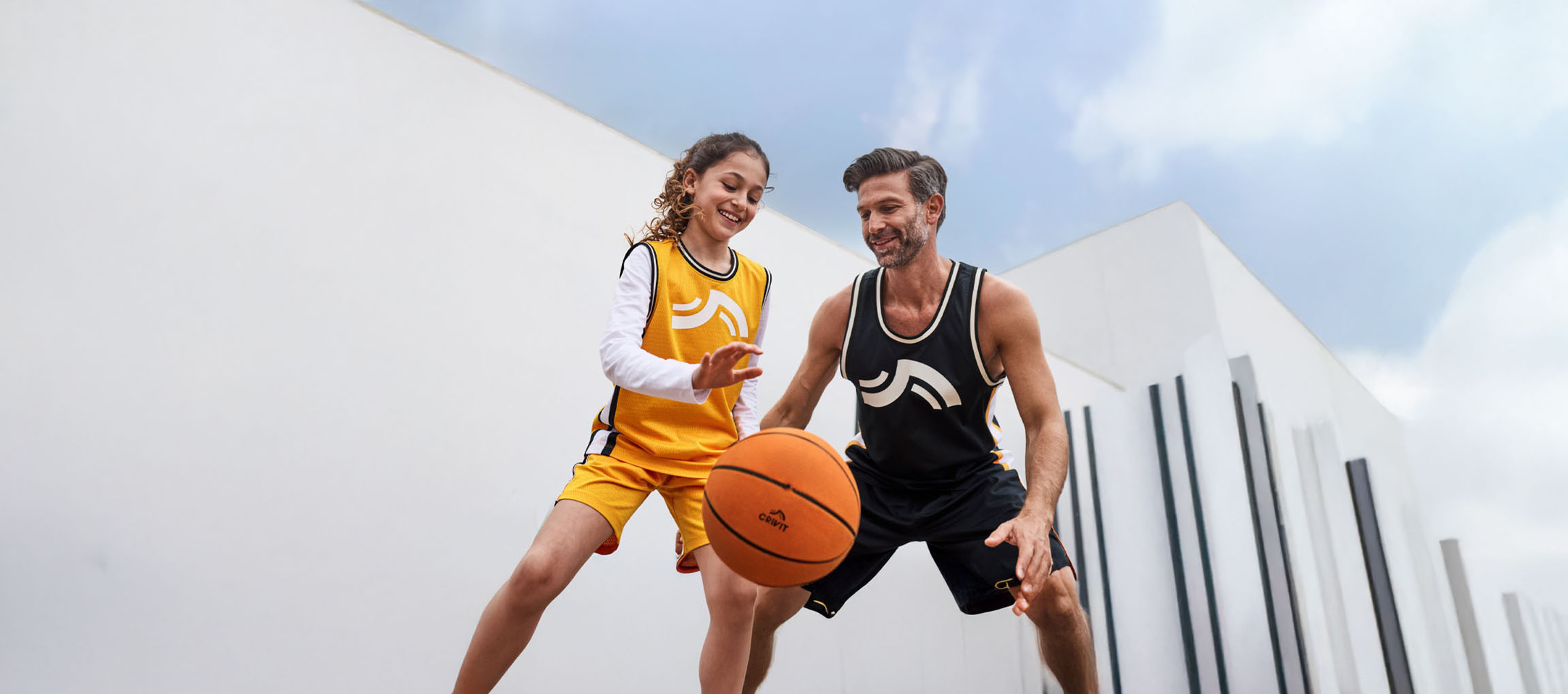 Vater und Tochter spielen Basketball in Basketballkleidung und mit Ball