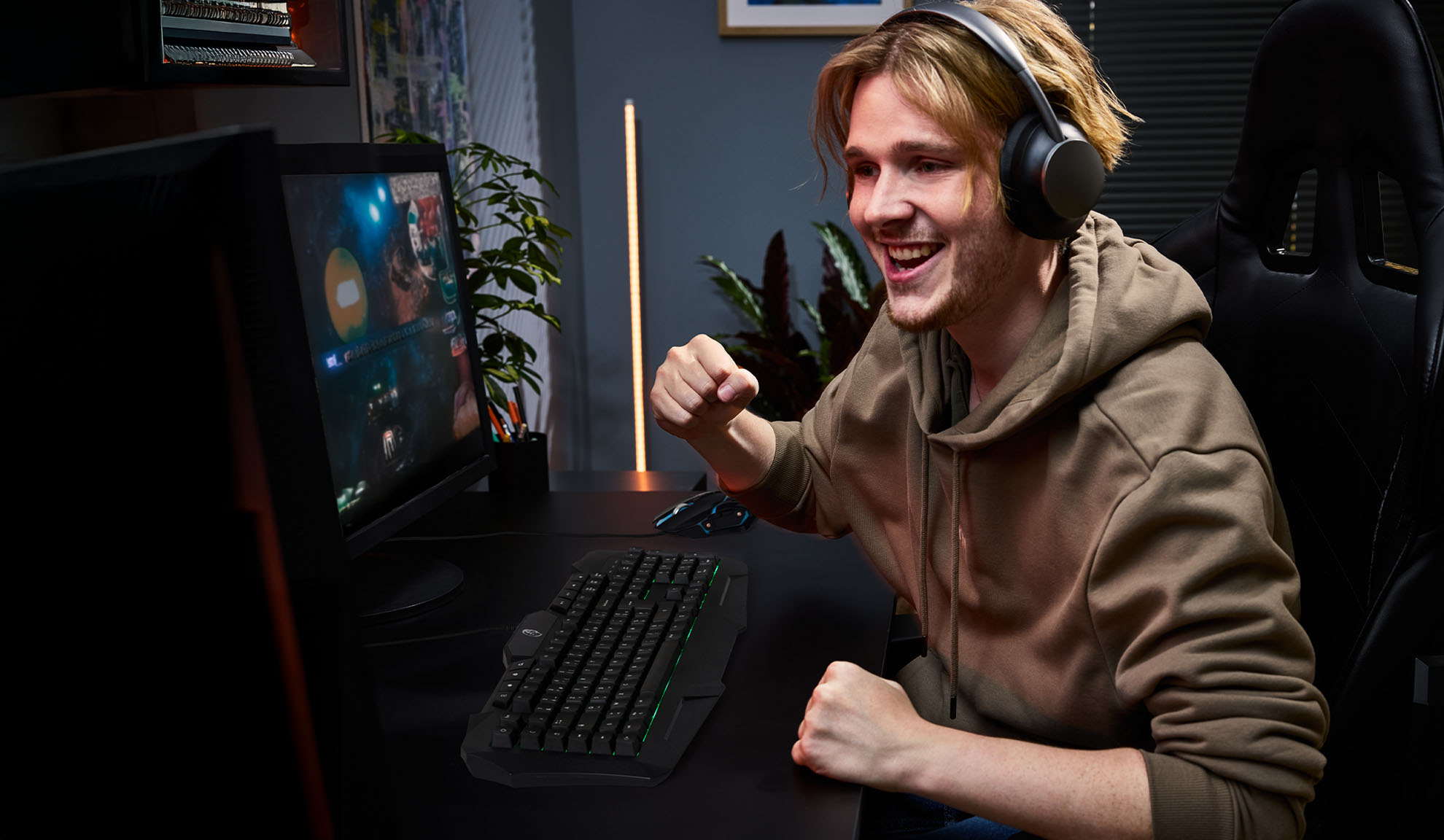 Jeune homme avec un casque jouant à des jeux vidéo avec un clavier et une souris de gaming.