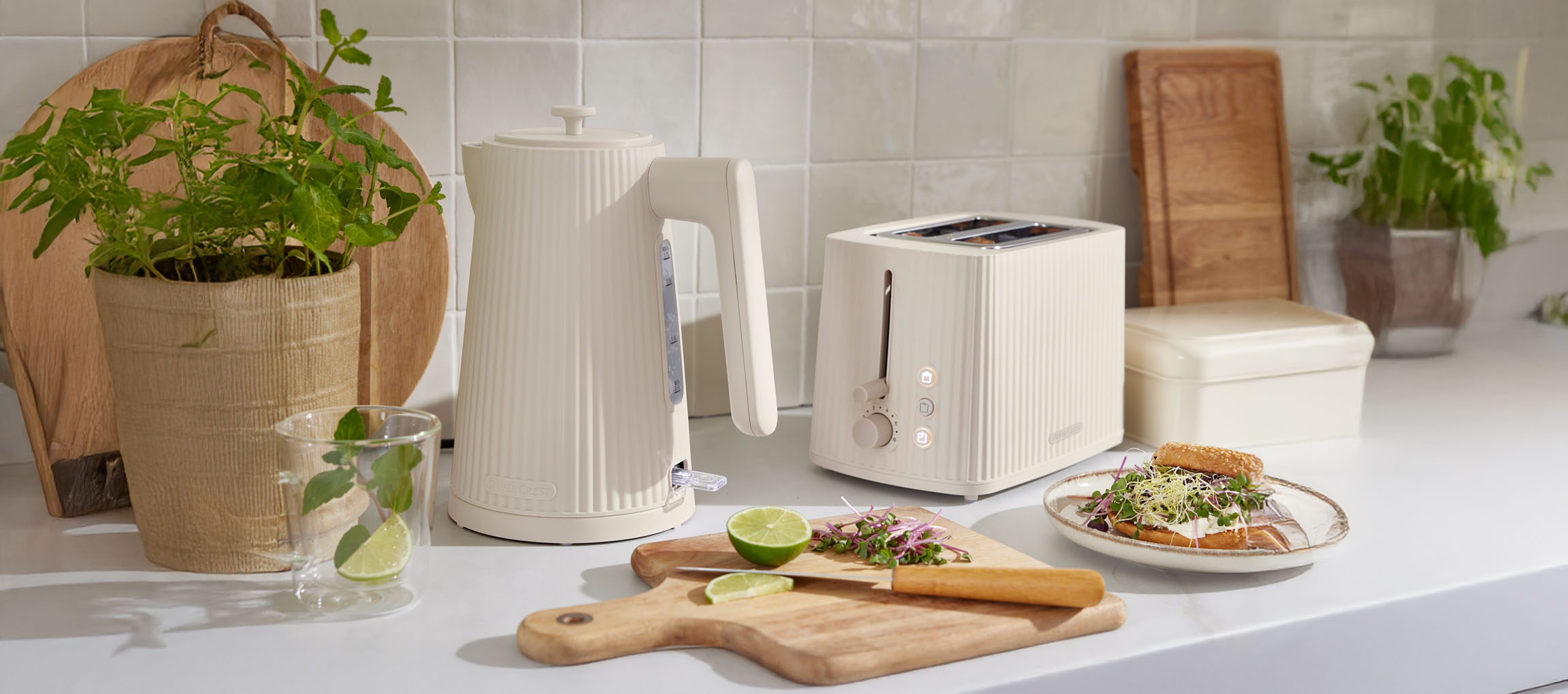 SilverCrest cremefarbener Wasserkocher und Toaster auf einer Küchenzeile mit Pflanzen und Essen.