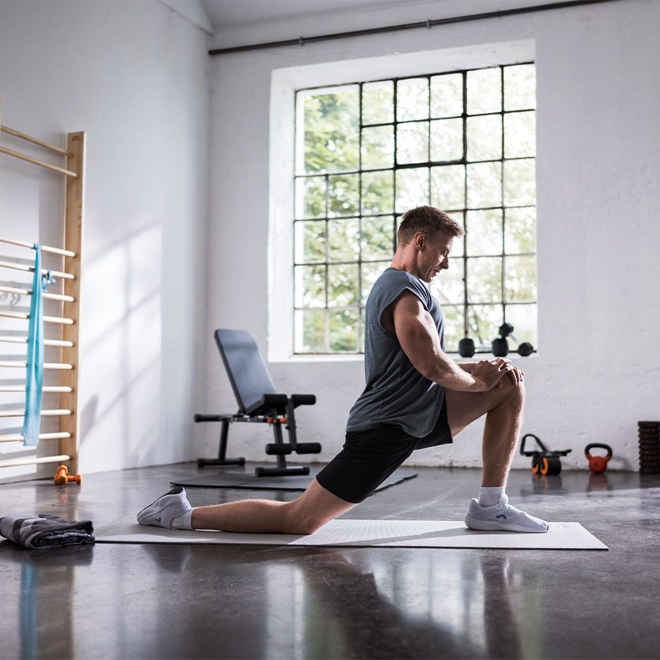 Mann dehnt sich auf einer Yogamatte im Fitnessstudio.