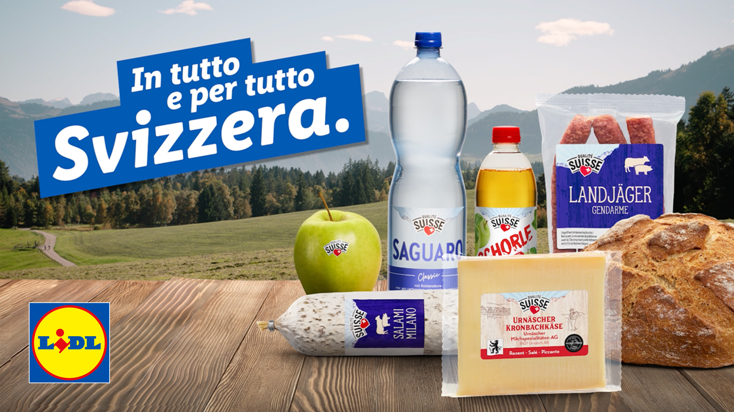 Prodotti svizzeri assortiti su un tavolo di legno con sfondo montano, con il testo 'In tutto e per tutto Svizzera'.