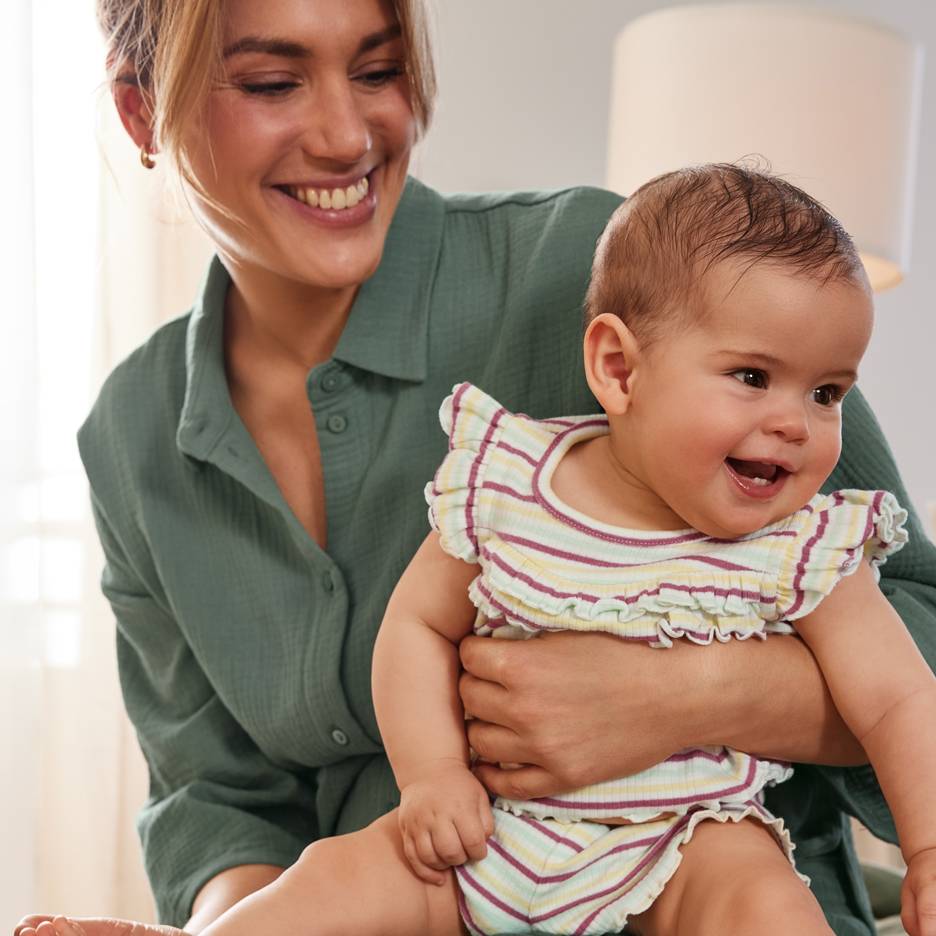 Mère souriante avec un bébé heureux portant une tenue rayée colorée.