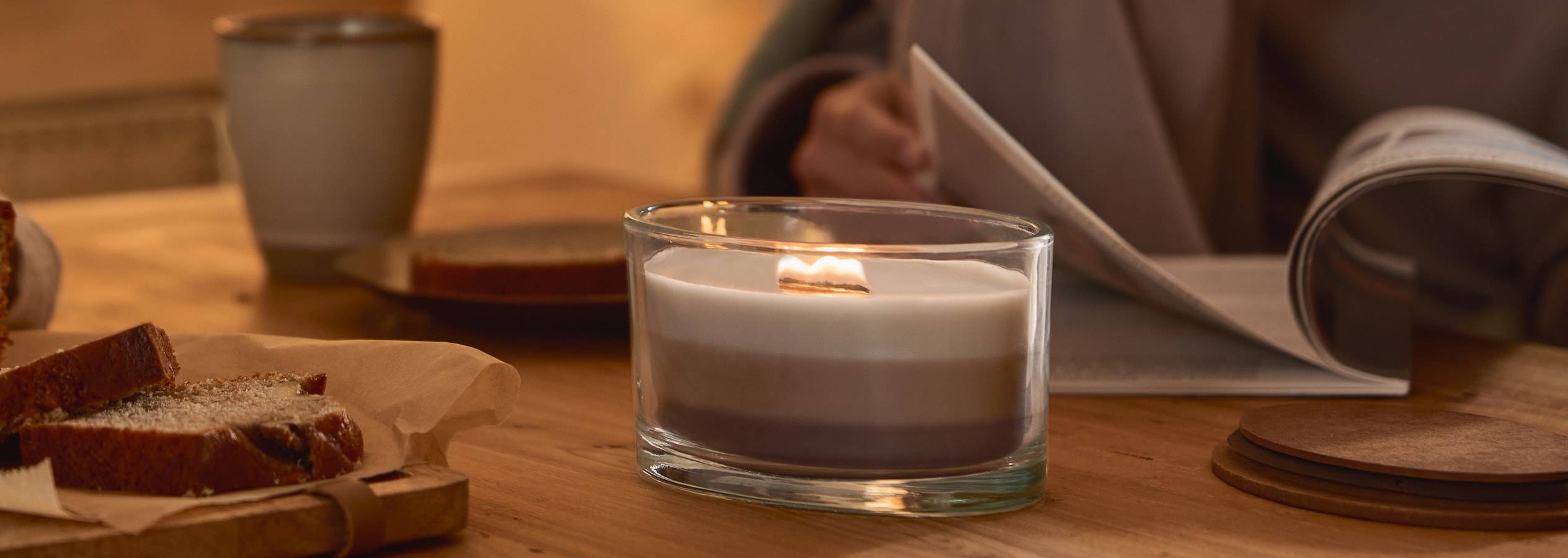 Candela a tre strati con stoppino in legno, pane e una persona che legge.