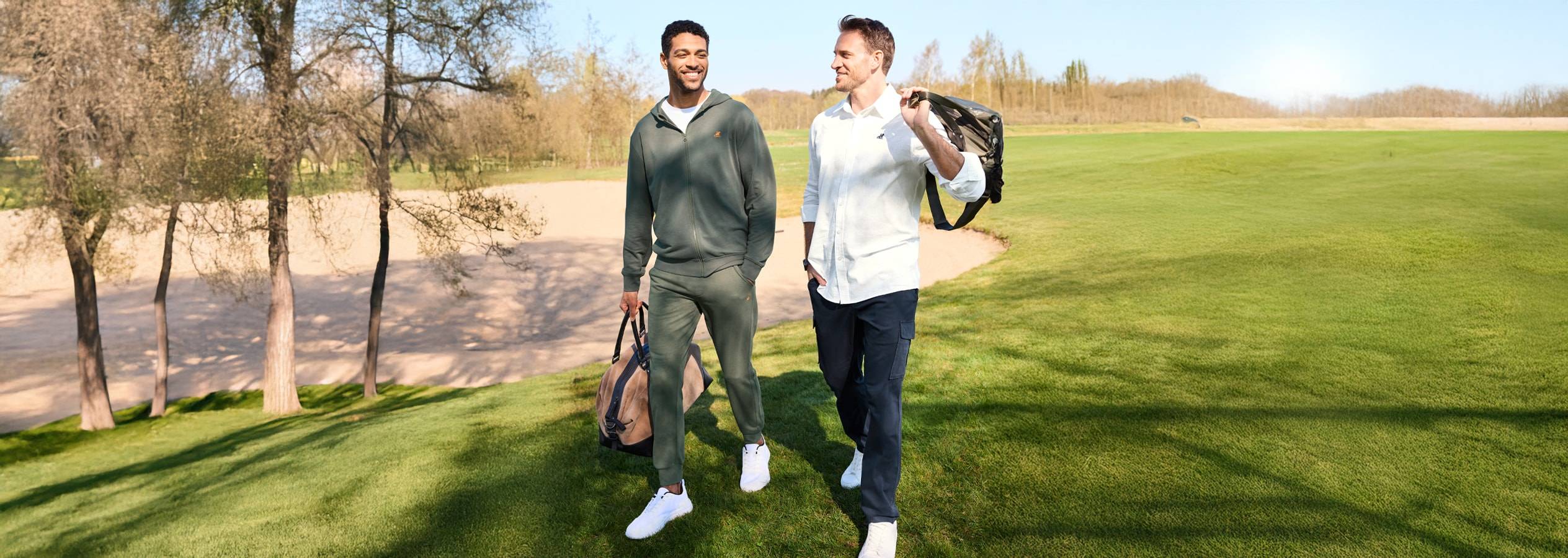 Zwei Männer in sportlicher Kleidung gehen über einen Golfplatz.