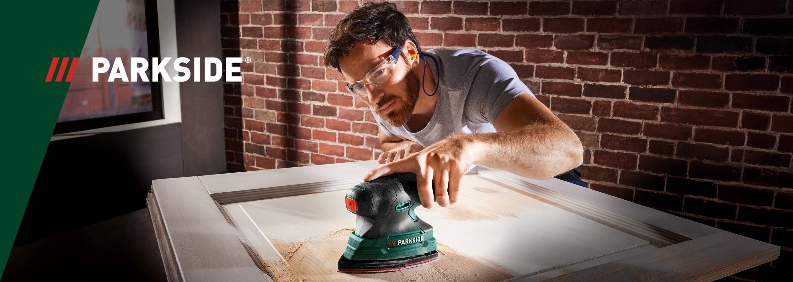 Un homme utilise une ponceuse Parkside pour poncer une porte en bois.