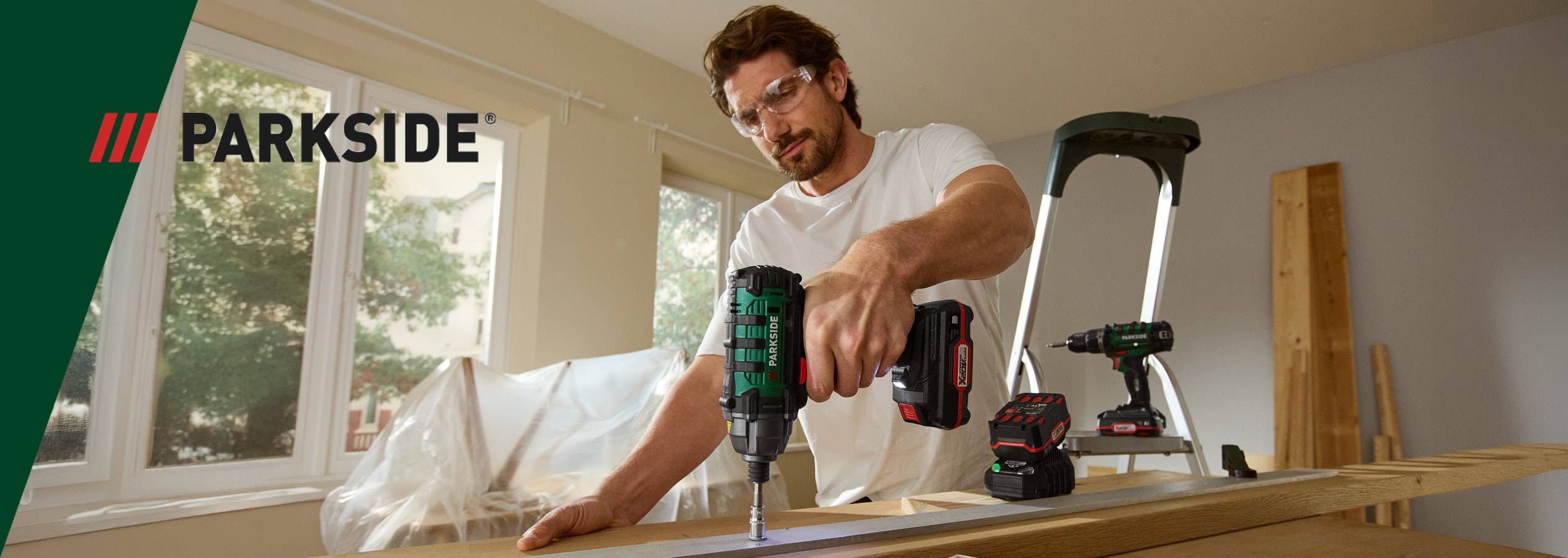 Un uomo usa un avvitatore a impulsi Parkside per avvitare una tavola di legno.