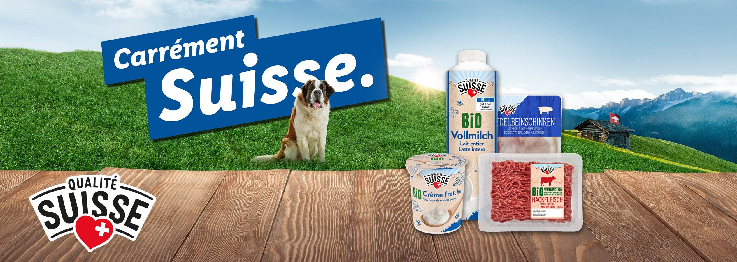Produits alimentaires suisses biologiques sur une table en bois avec un fond de montagne et un Saint-Bernard.