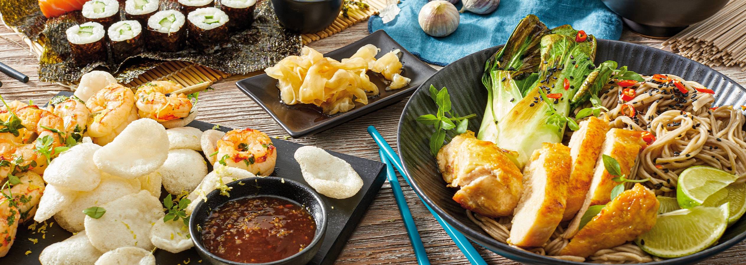 Un festin asiatique avec des sushis, des brochettes de crevettes, des nouilles soba et du poulet.