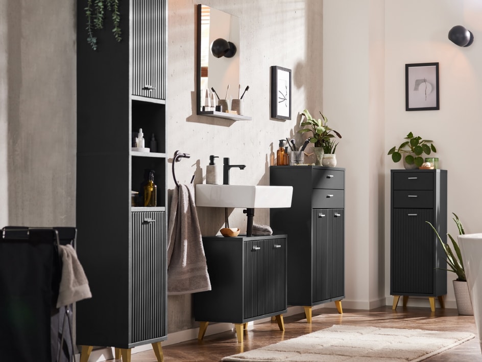 Ein modernes Badezimmer mit schwarzen Möbeln, hellen Holzdetails, einem weißen Waschbecken und Pflanzen.