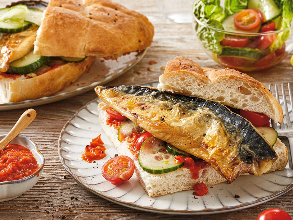 Makrelen-Sandwiches mit Gurken, Tomaten und roter Soße, dazu ein Beilagensalat.