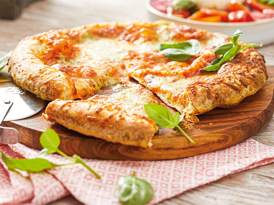 Selbstgemachte Pizza mit Mozzarella und Basilikum, auf einem Holzbrett serviert.