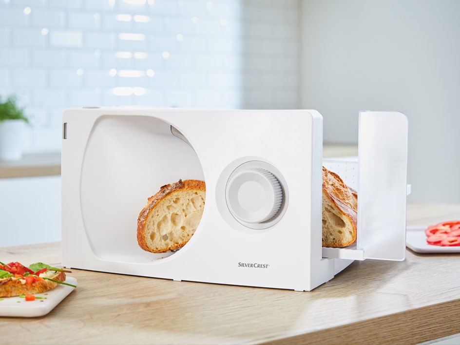 Eine weiße SilverCrest Brotschneidemaschine schneidet ein Brot.