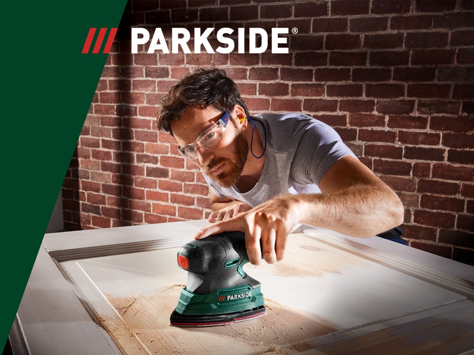 Un homme utilise une ponceuse Parkside pour travailler le bois.