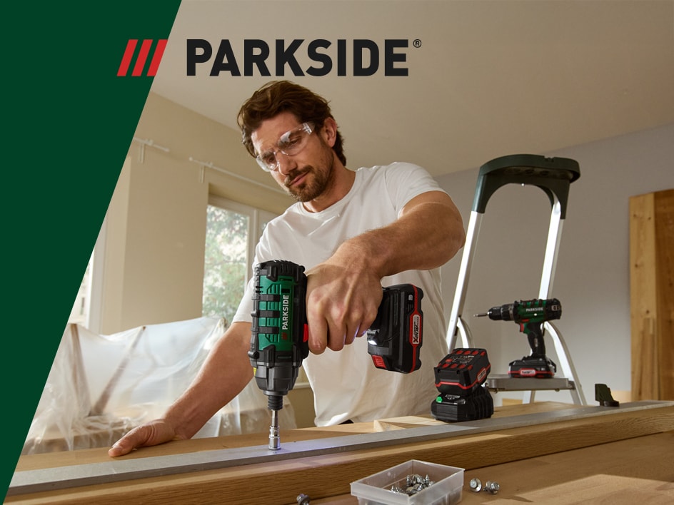 Un uomo usa un trapano avvitatore Parkside per avvitare una tavola di legno.